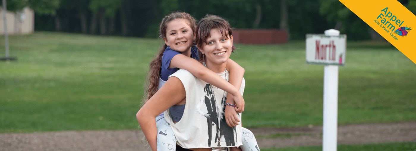 Person giving a camper a piggyback ride.